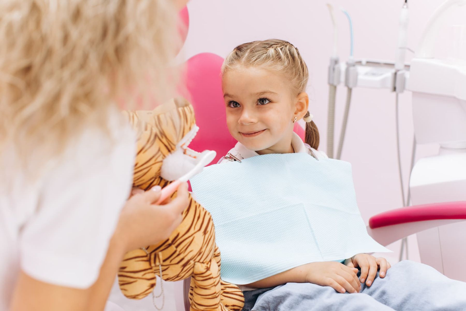 Lachend meisje met knuffel in de behandelstoel
